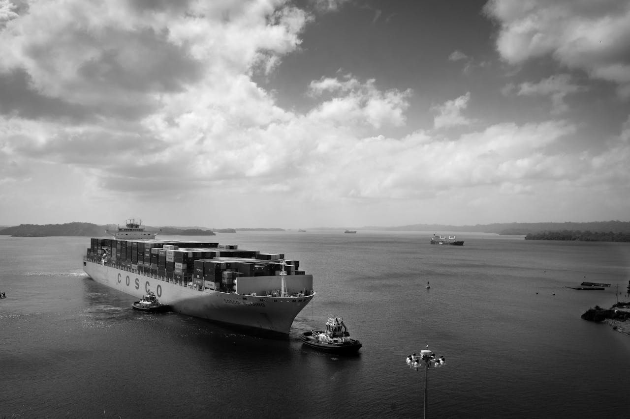 about-02 Black and white image of a large container ship navigating through calm waters.